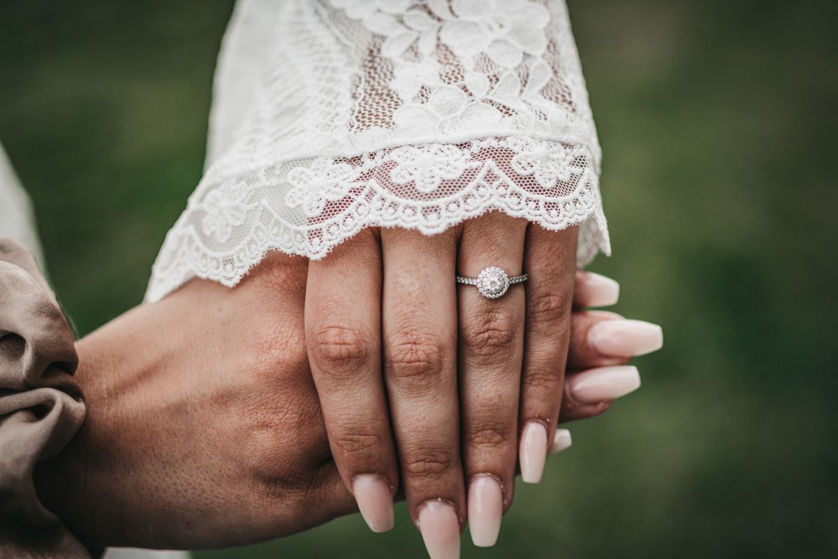 Close-up of a bride's hand showcasing a diamond ring with a lace sleeve in Stockholm.