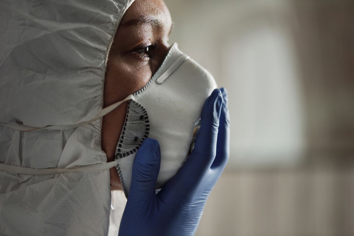 Close-up of a healthcare worker wearing a protective suit, mask, and gloves.