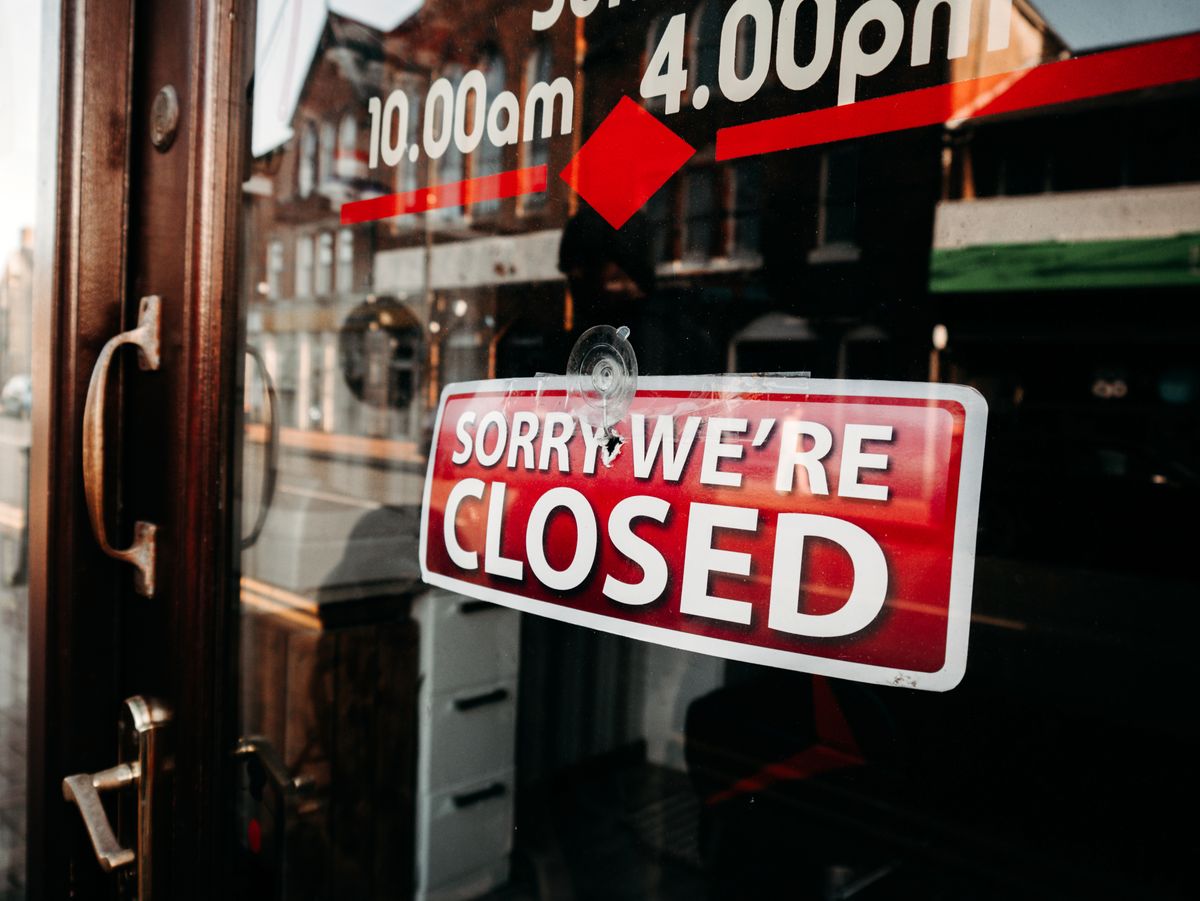 Starting a Food Business: 12 Hard Truths Most New Owners Realize Too Late 1 Close-up of a shop's closed sign on a glass door reflecting the street outside.