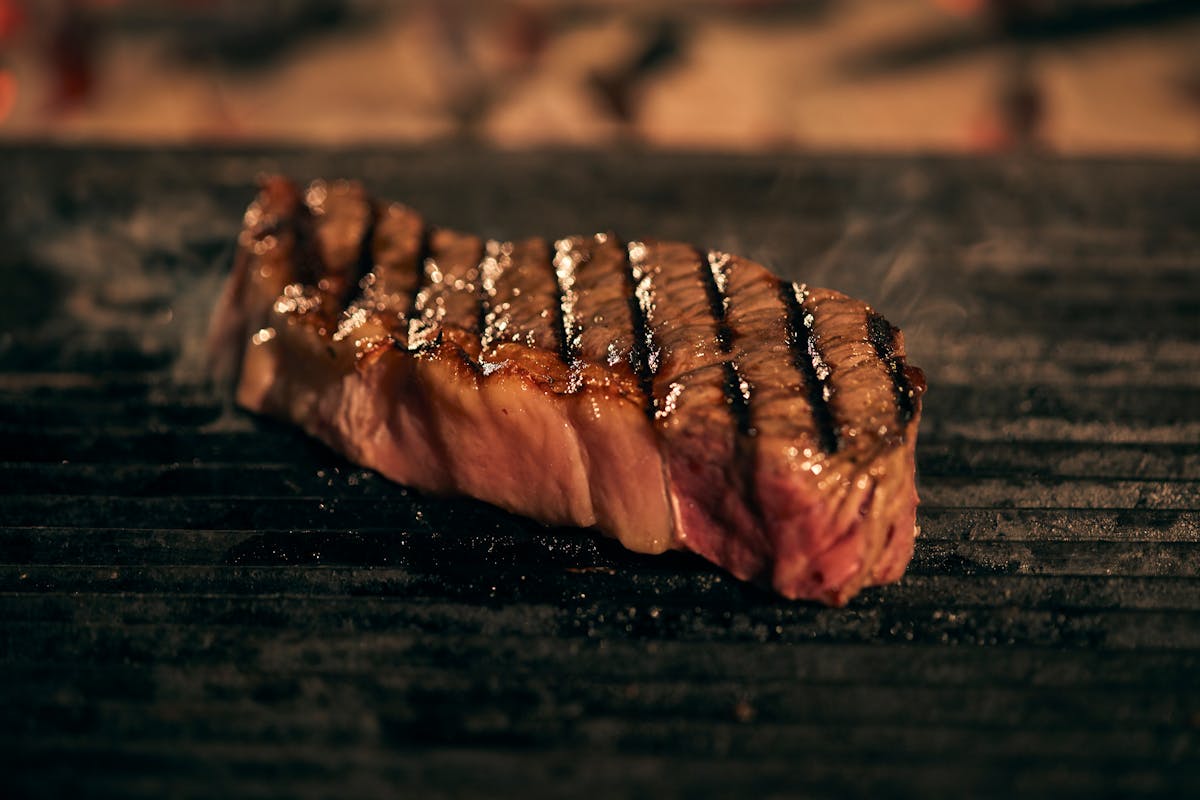 Stop Wasting Money: What Grocery Stores Don’t Want You to Know About Ribeye Steaks 3 Close-up of a tender, juicy steak grilling on a hot barbecue, showcasing mouthwatering char marks.