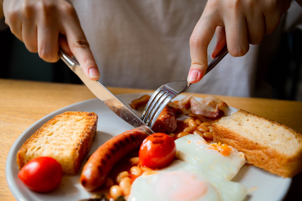 Close-up of a traditional English breakfast with sausage, eggs, beans, and toast.
