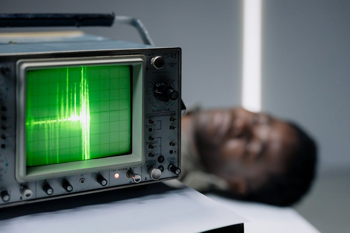 Scientists Found Something Creepy Your Brain Does Under Anesthesia 2 Close-up of a vintage oscilloscope displaying a green waveform next to a blurred person.