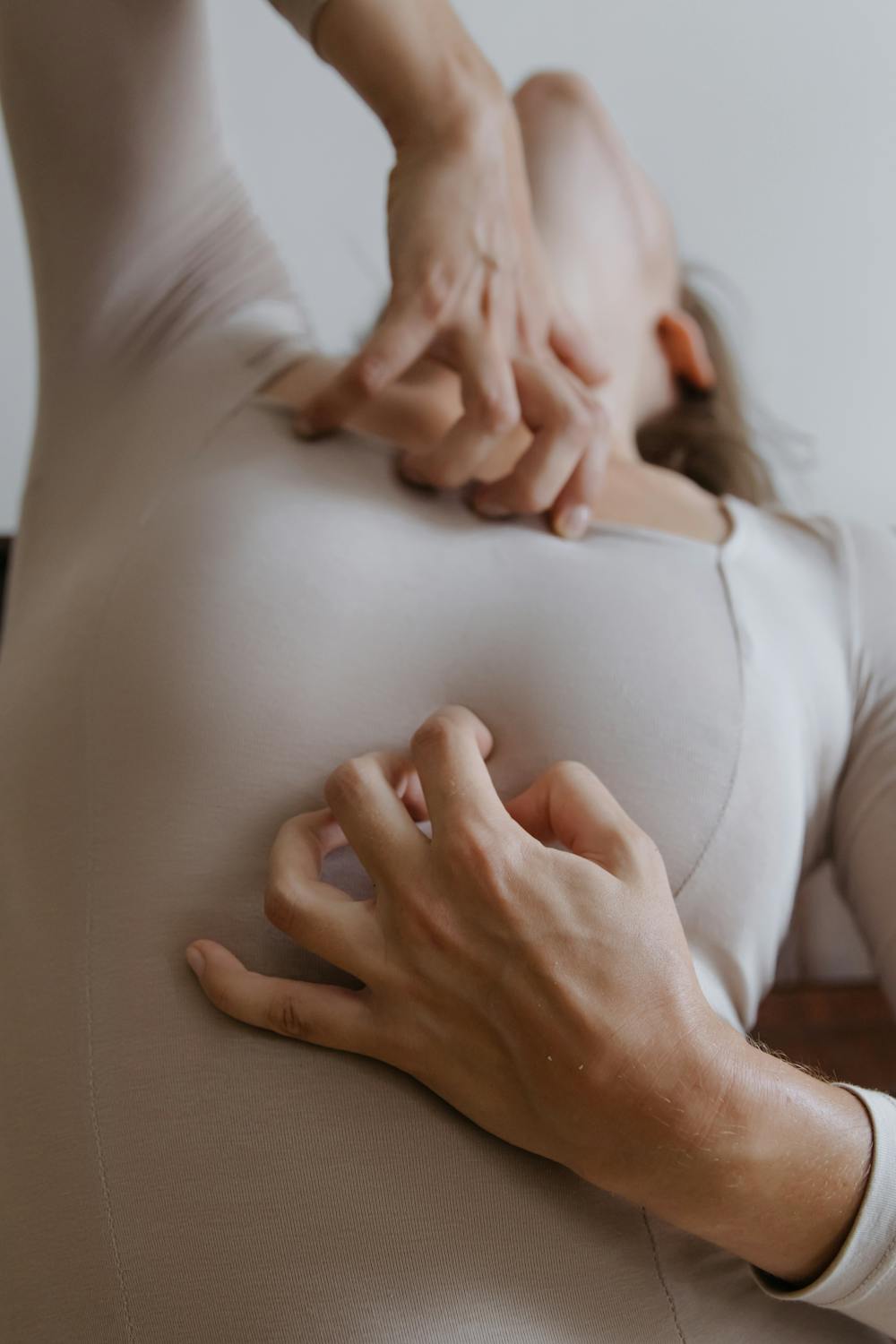 Close-up of a woman's hands scratching her skin, showcasing relief and comfort in a beige environment.