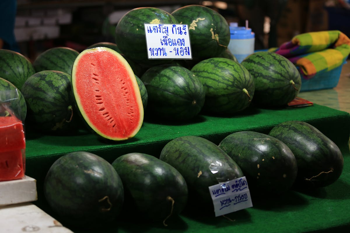 Close-up of fresh watermelons on display at a Bangkok market. Vibrant colors and textures enhance appeal.