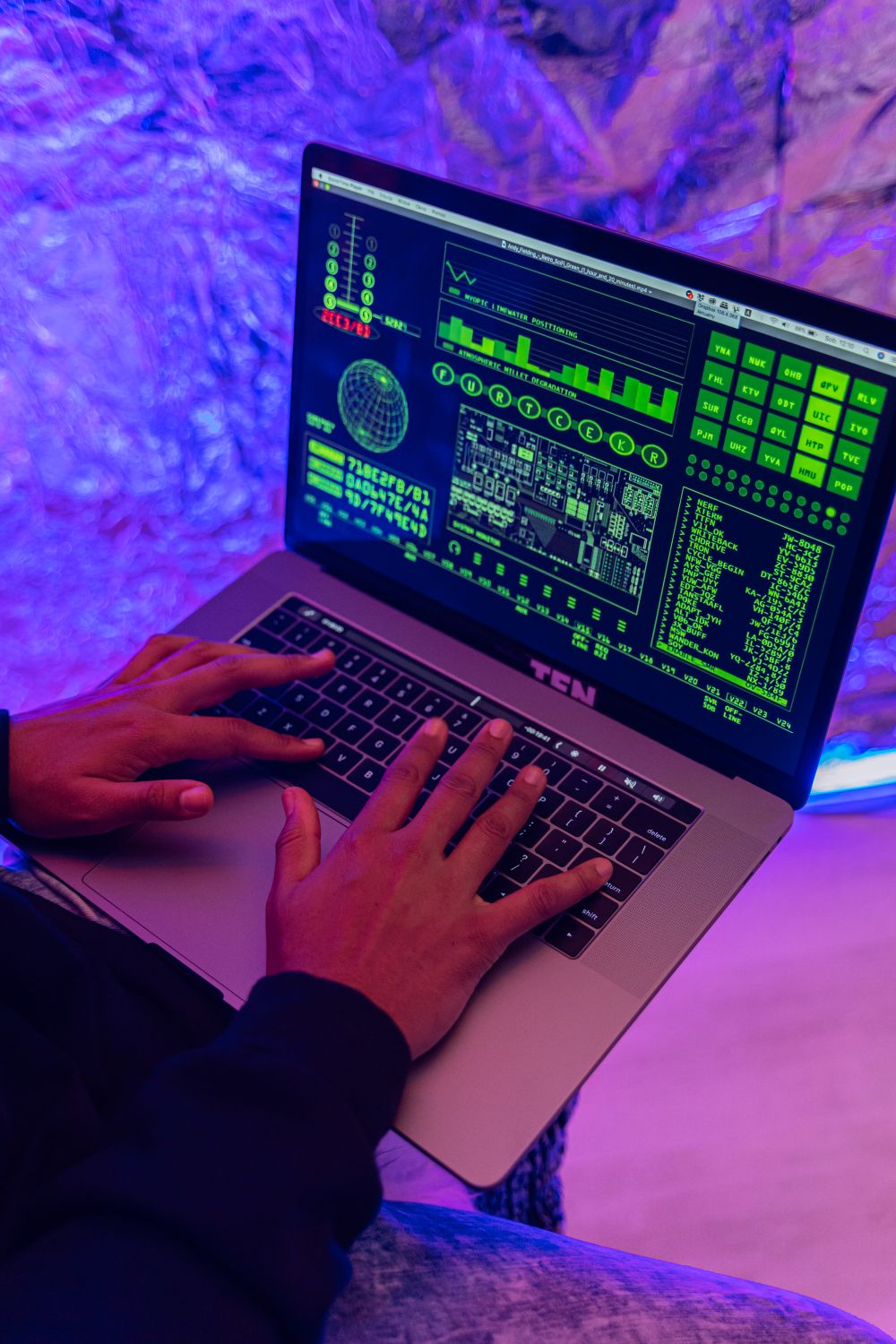 10 Job Skills You’re Ignoring That Are Killing Your Career 2 Close-up of hands typing on a laptop displaying green code, indoors, purple lighting.
