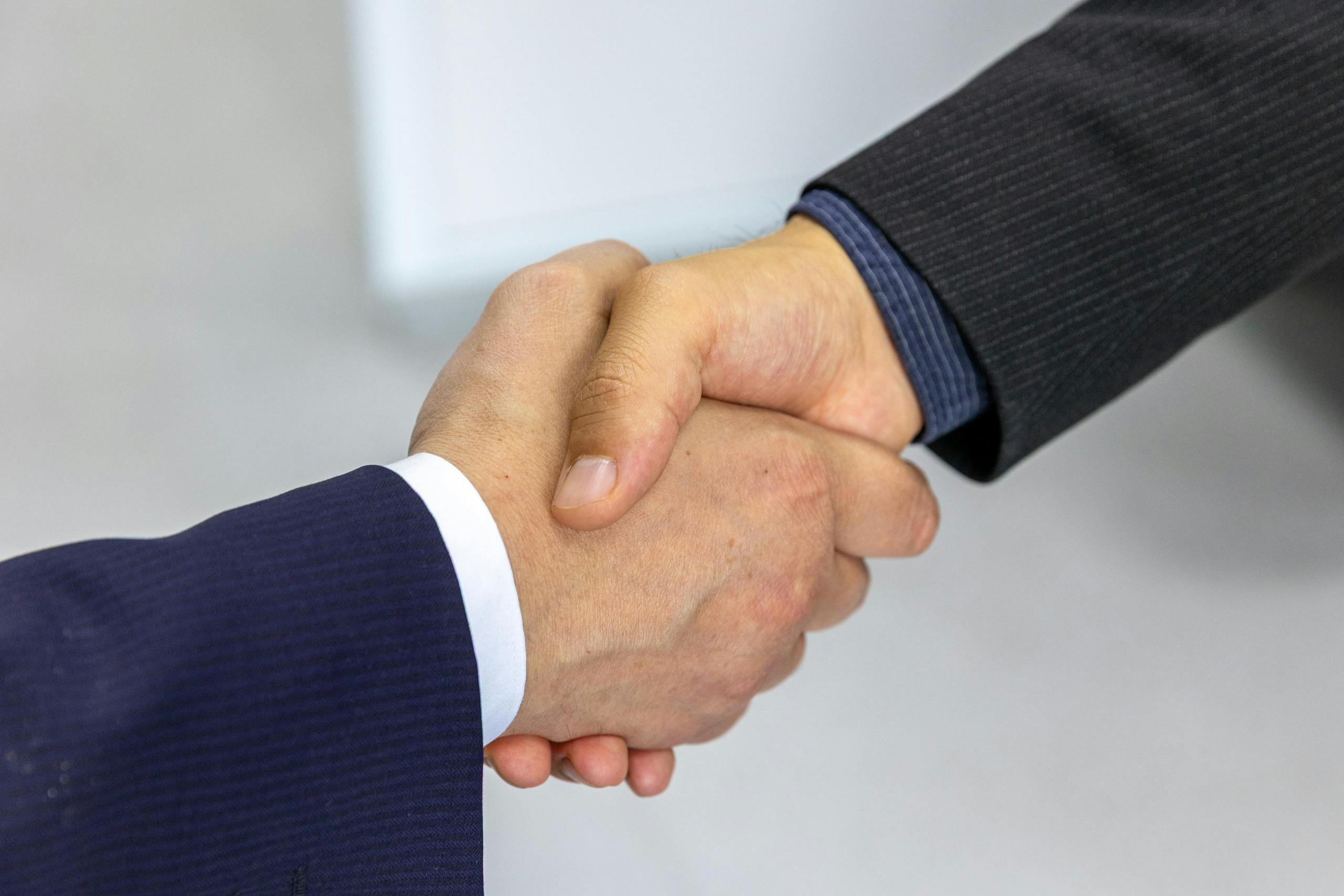 Trump’s Saudi Nuclear Agreement Opens Door to Uranium Enrichment and a High-Stakes Fight in Congress 2 Close-up of two businessmen shaking hands, symbolizing agreement and partnership.
