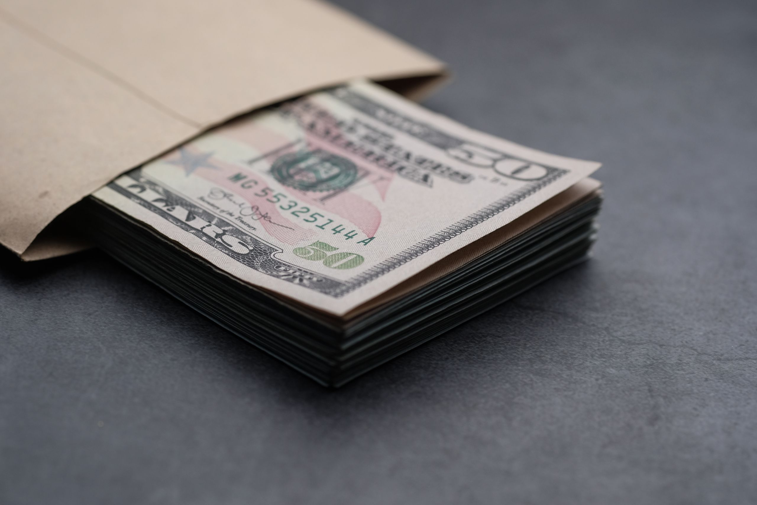 Trump’s White House Ballroom Donors Now Face a $50B Question as Americans Struggle With Bills 2 Close-up of US fifty dollar bills partially enclosed in a brown envelope, symbolizing finances.