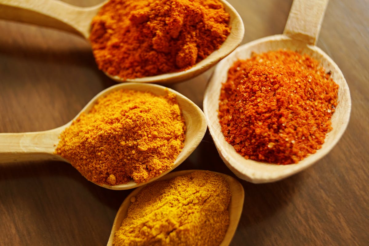 6 Popular Foods With Hidden Lead Risks 1 Close-up of vibrant spices like turmeric and chili powder in wooden spoons.