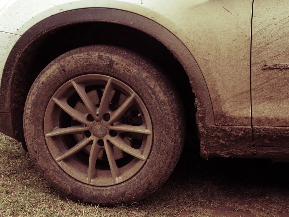 13 Gas Station Mistakes That Are Quietly Draining Your Wallet 4 Close-up view of a car wheel covered in mud, highlighting off-road adventures.