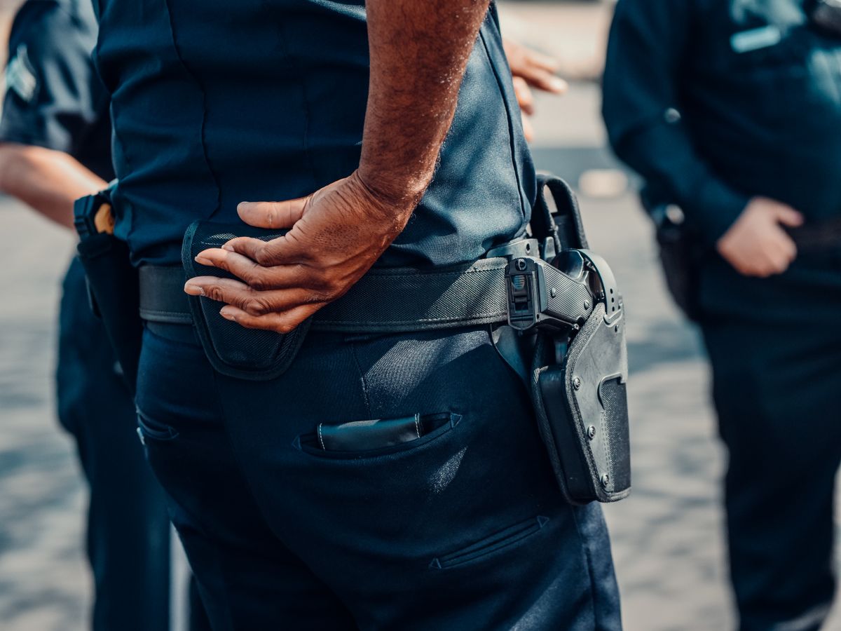 Close-up view of a police officer in uniform with a focus on the holster and handgun.