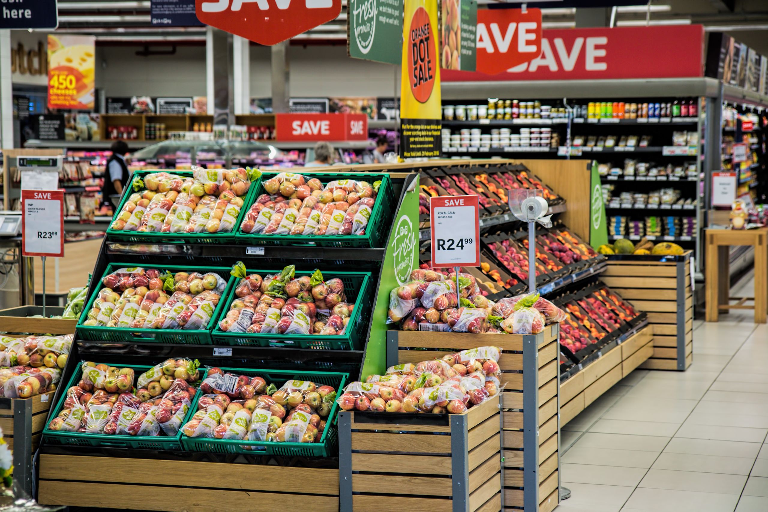 9 Reasons Walmart and Kroger’s Price Cuts Feel Like a Grocery War Shoppers Can’t Ignore 2 Colorful produce aisle in a supermarket showcasing fresh apples with discount signage.
