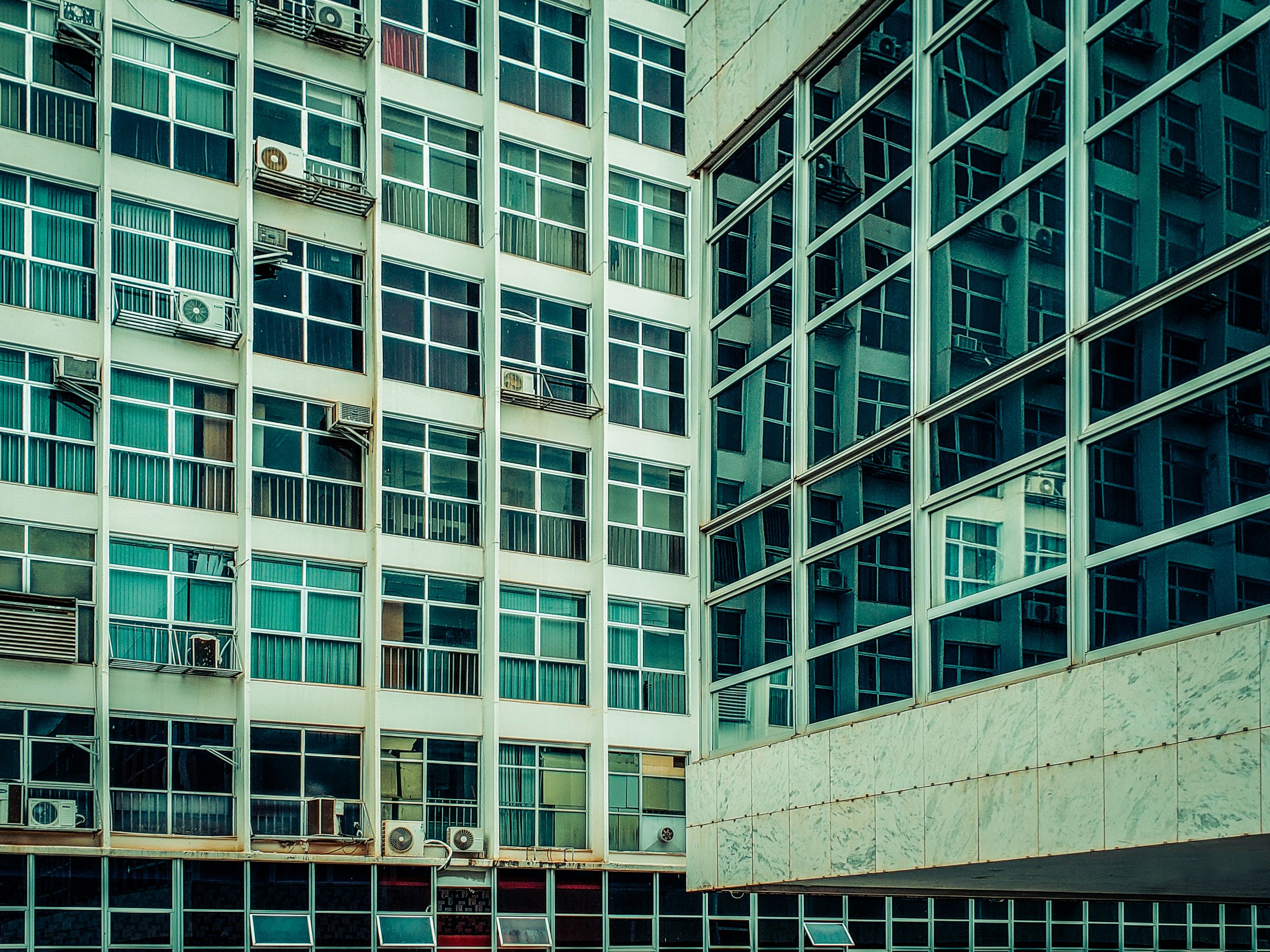 Arizona’s Summer Electricity Shock Is Back, and This Time It Feels Personal as Air Conditioning Becomes a Daily Financial Struggle 2 Converging urban buildings with reflective glass and numerous windows seen from below.