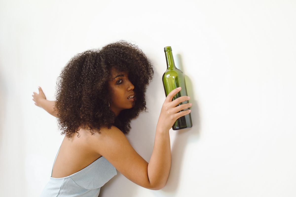 Creative portrait of a woman holding a green bottle, adding a moody aesthetic.