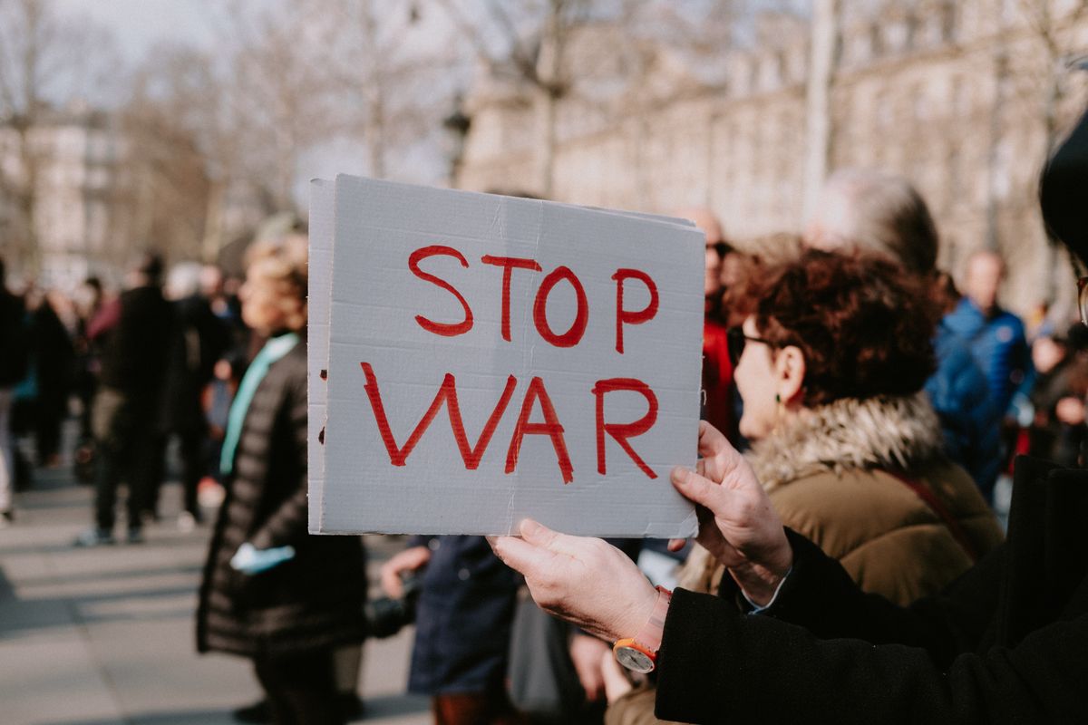 Trump Iran Deal Poll Reveals a Deeper Crisis: Americans Want Peace, Not Confidence 1 Crowd of people in a peaceful protest holding a 'Stop War' sign outdoors.