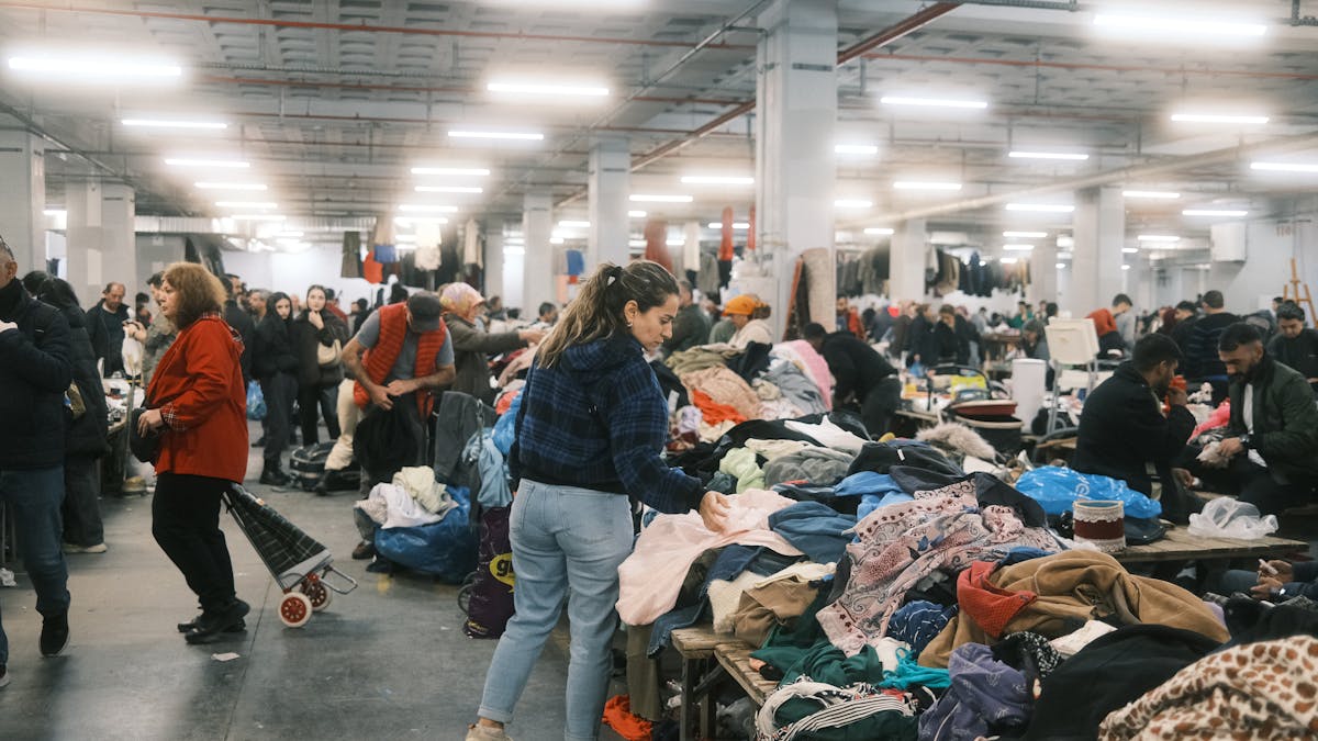 Crowded indoor flea market in Istanbul with people browsing textiles and clothes.