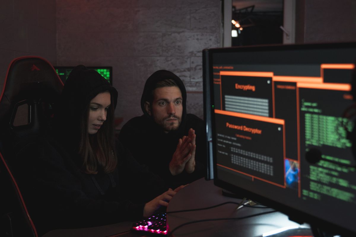 Going Global Can Grow a Business Fast. It Can Also Expose Every Weak Spot. 4 Cybersecurity experts in hoodies analyzing encrypted data on computer screens in an indoor setting.