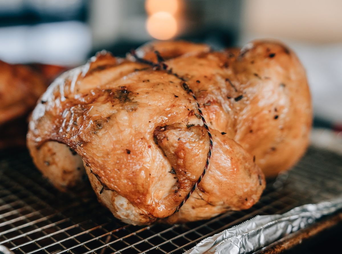 Delicious close-up of a perfectly roasted chicken seasoned with herbs, ideal for food photography.