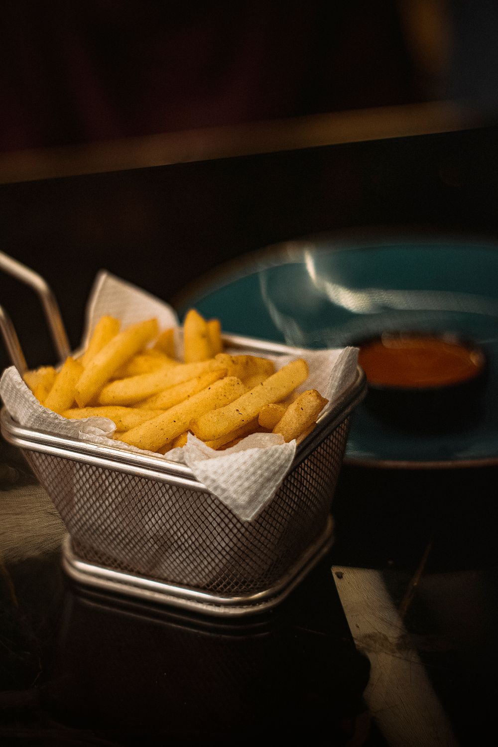 Delicious crispy French fries served in a basket with a side of dipping sauce.