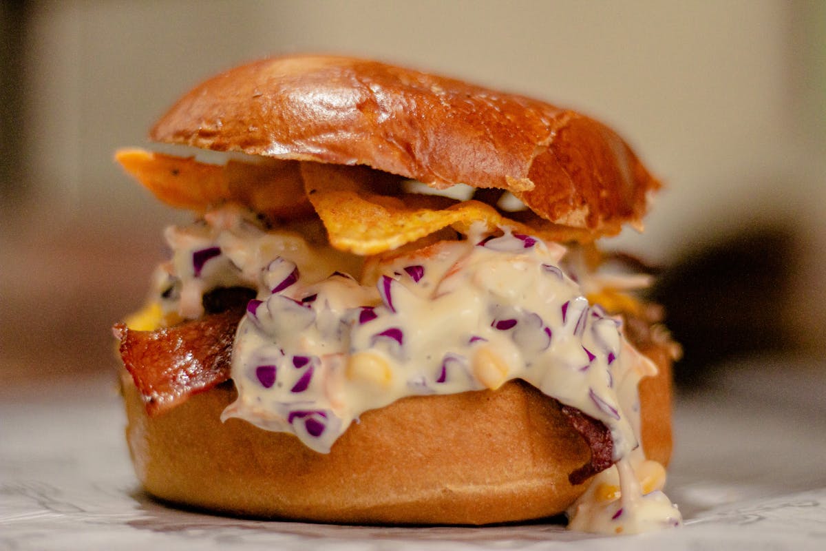Delicious gourmet sandwich with melted cheese, chips, and purple cabbage.