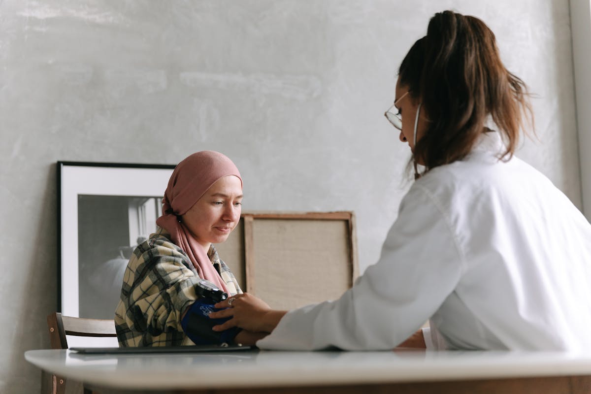 Terrifying Cancer Symptoms People Ignore Until It's Too Late 1 Doctor checks blood pressure of a patient wearing a headscarf indoors, focused on healthcare.