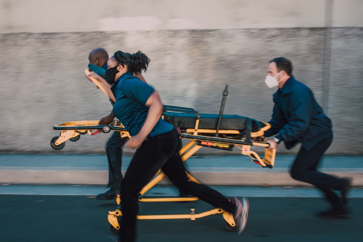 Venezuela Earthquake Death Toll Tops 1,400 As Rescue Teams Race Through Rubble, Aftershocks And A National Emergency 1 Dynamic shot of paramedics running with a stretcher on a street, showcasing urgency and teamwork.