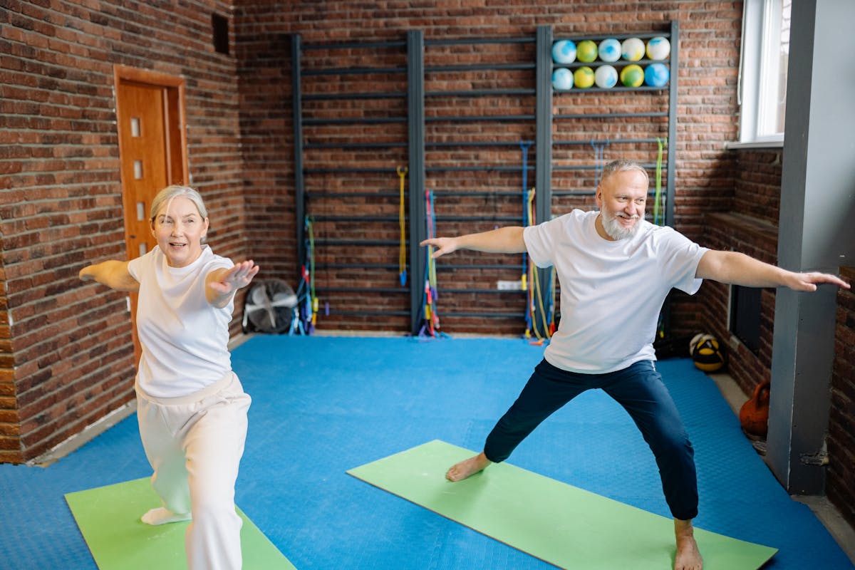 7 Shocking Truths About How Often You Should Shower as You Get Older 2 Elderly couple doing yoga poses on mats in a gym, promoting active lifestyle.