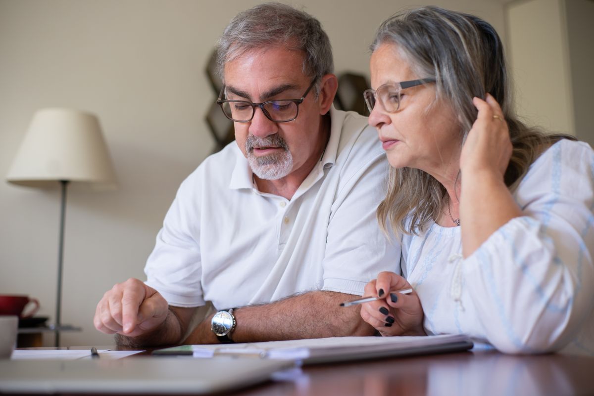 The Highest and Lowest Pensions in the U.S., According to New Data 1 Elderly couple enjoying leisure time with crosswords at home, showcasing togetherness.
