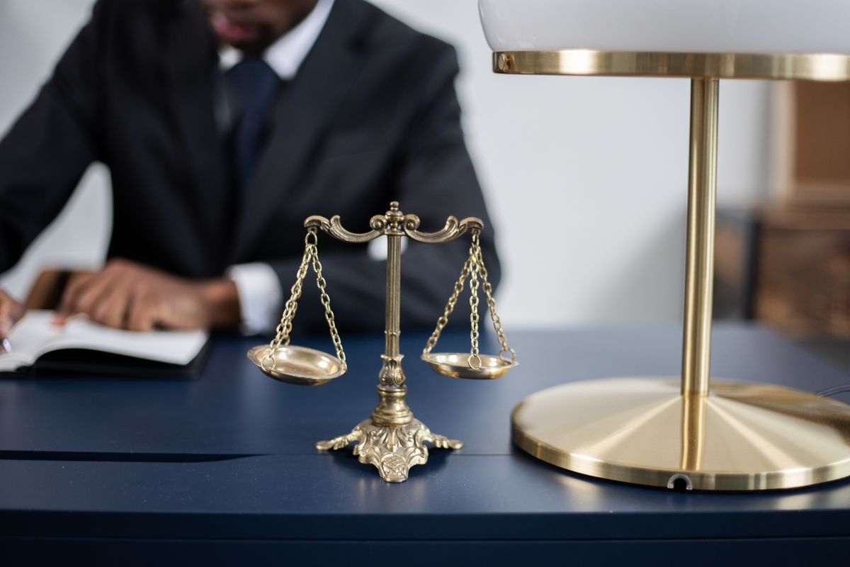 USPS Ballot Mail Proposal Turns the Mailbox Into the New 2026 Election Battleground 2 Elegant legal office with a close-up of golden scales of justice on a sleek dark desk.