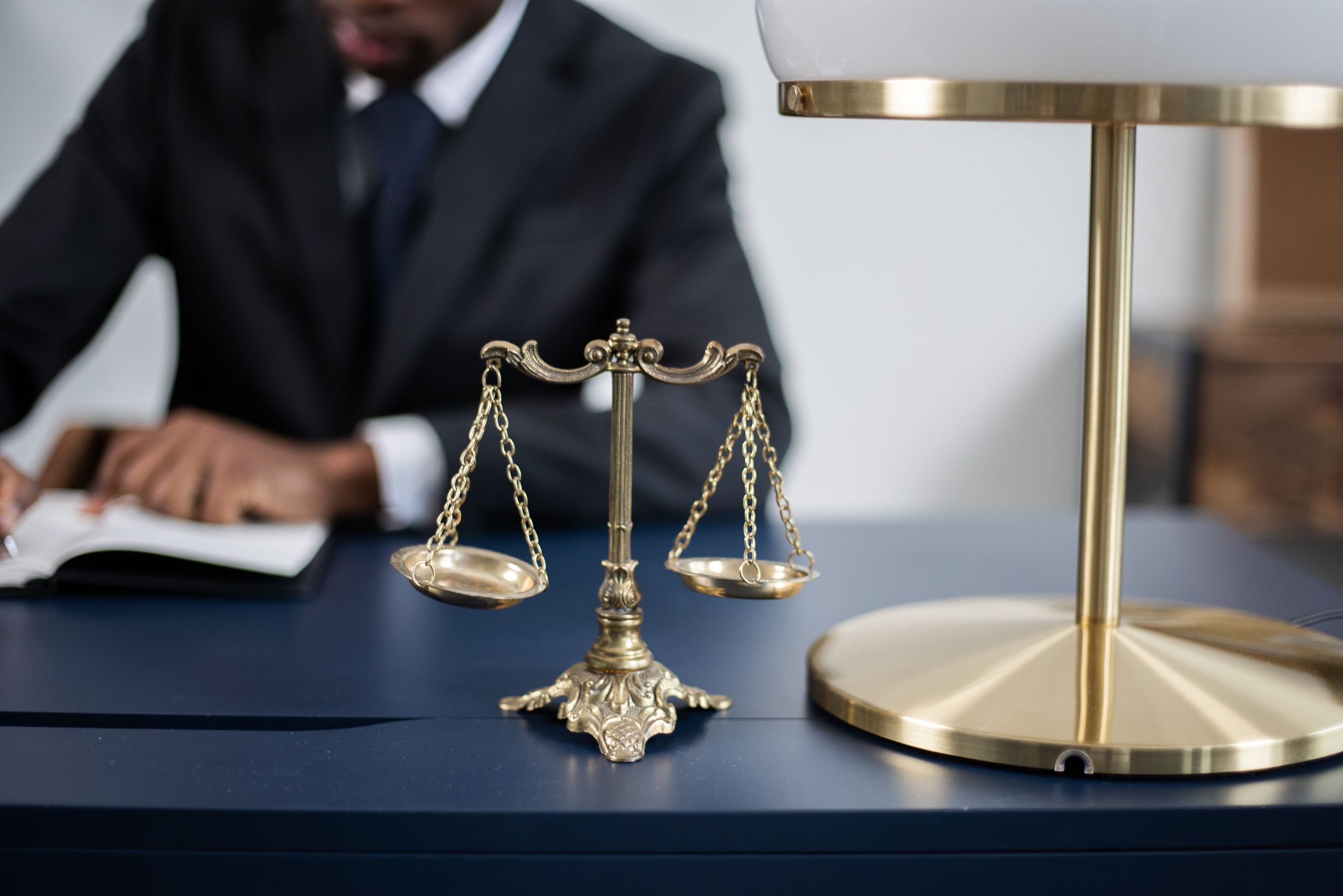 Army Captain Sentenced to 12 Years After Pregnant Soldier Was Secretly Given Abortion Drug 2 Elegant legal office with a close-up of golden scales of justice on a sleek dark desk.