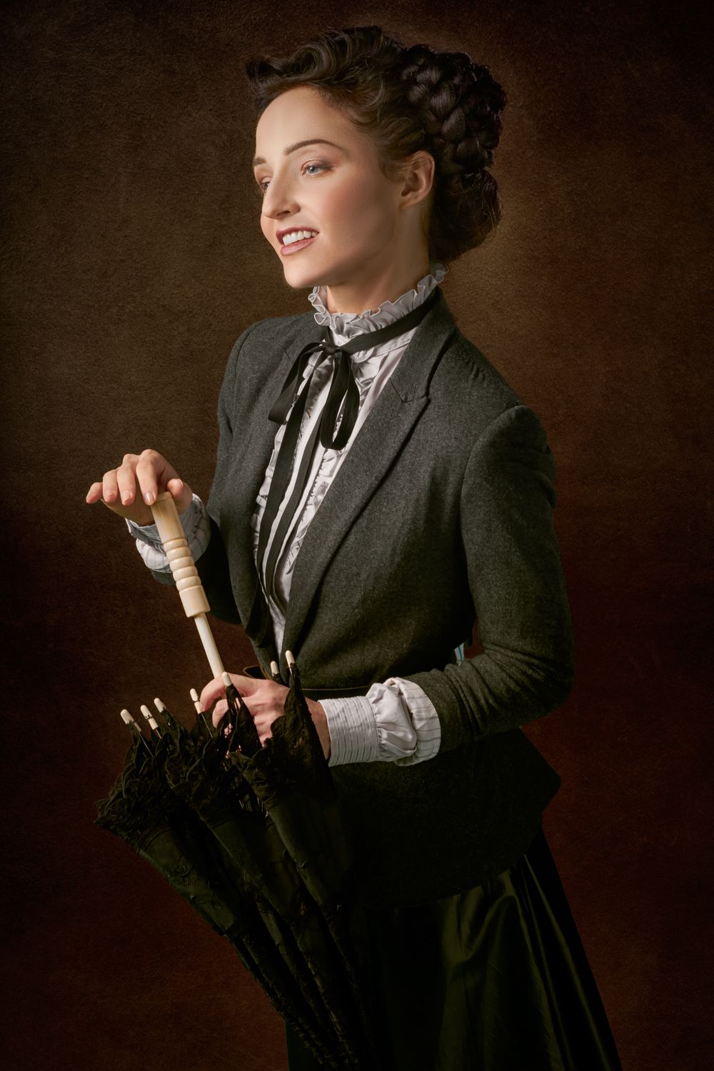 Elegant woman in vintage attire holding an umbrella with a smile.