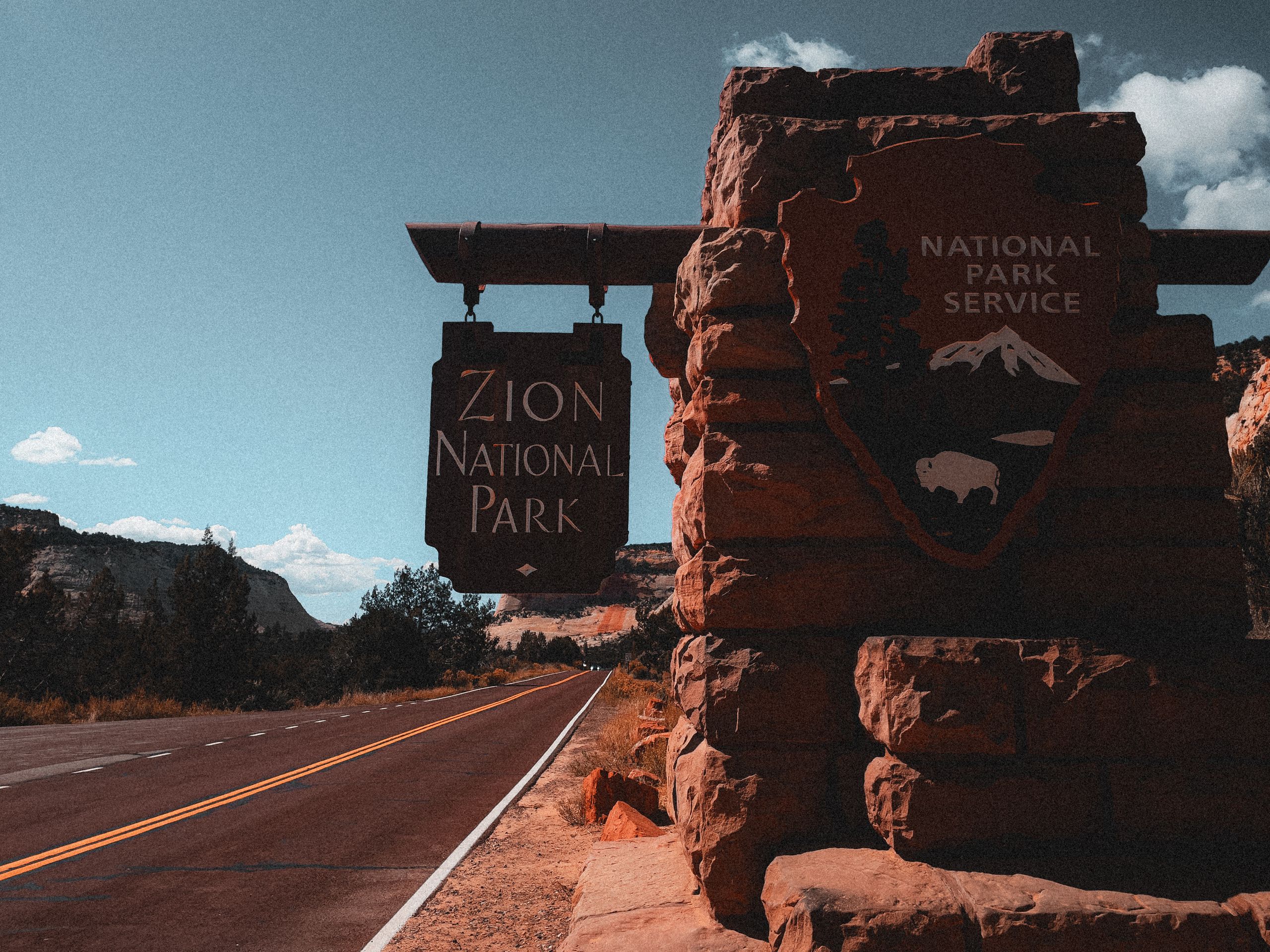 Explore Zion National Park with its iconic entrance sign along a picturesque road in Utah.