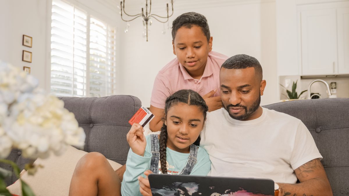 What Happens If You Do Not Pay a Deceased Person’s Credit Card Debt 4 Father and children using a laptop for online shopping at home, bonding over e-commerce activities.