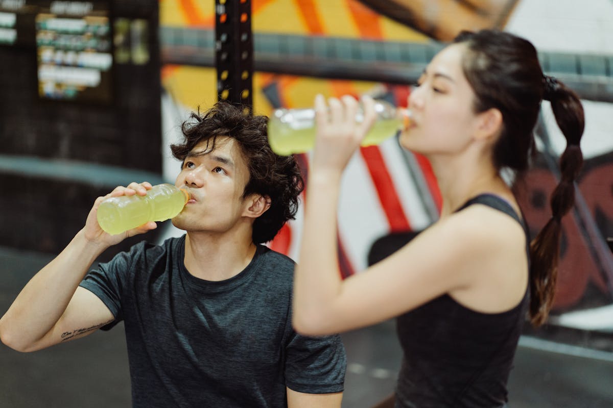 8 Weight Loss Killers Hiding In Your Daily Diet 1 Fit Asian couple hydrating at the gym after an intense workout. Refreshing drink break.