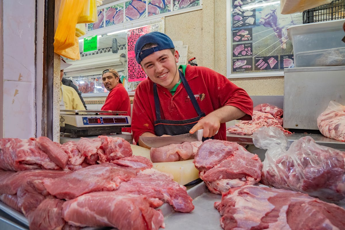 Friendly butcher cutting meat at a local market in Guanajuato, Mexico.