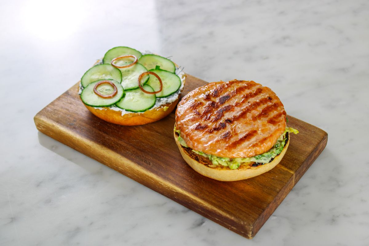 San Antonio Burger Favorite Smash’d Plans Major Expansion Near Pearl District 2 Grilled salmon burger with toppings on a wooden board, perfect for a tasty meal.