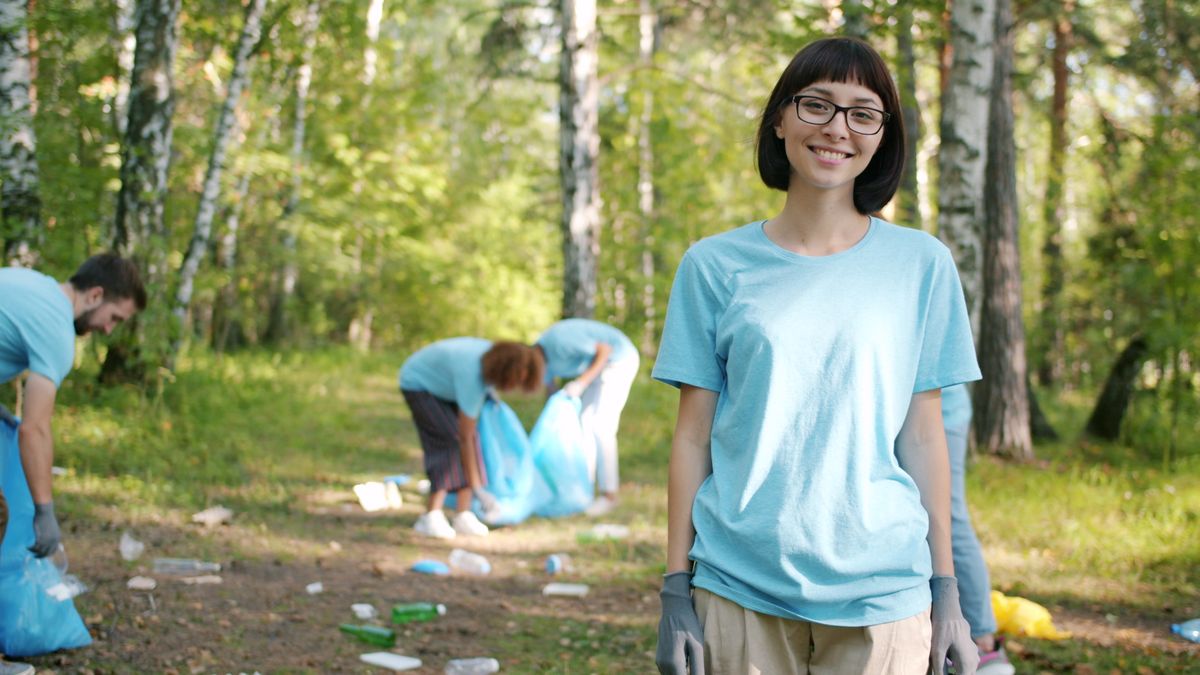 Group of volunteers collecting litter in a forest, focusing on environmental conservation.
