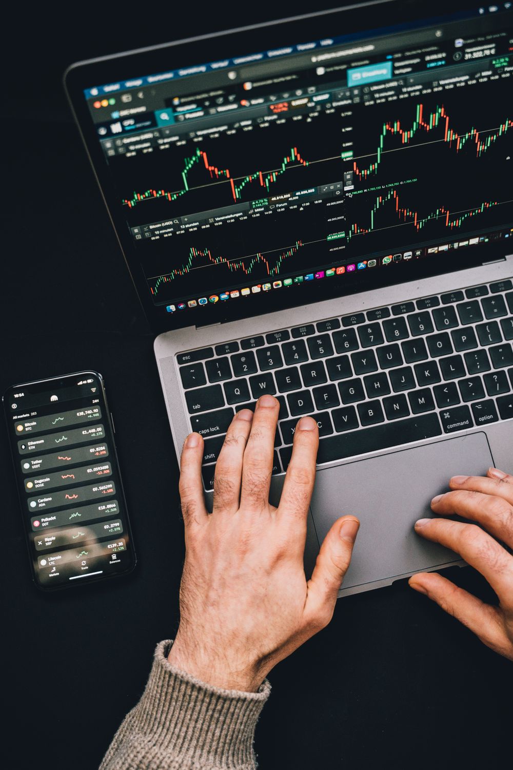 Data-Driven Strategies for Entering the African Market: A Modern Business Playbook 3 Hands typing on a laptop with cryptocurrency charts and smartphone display in view, focusing on digital finance.