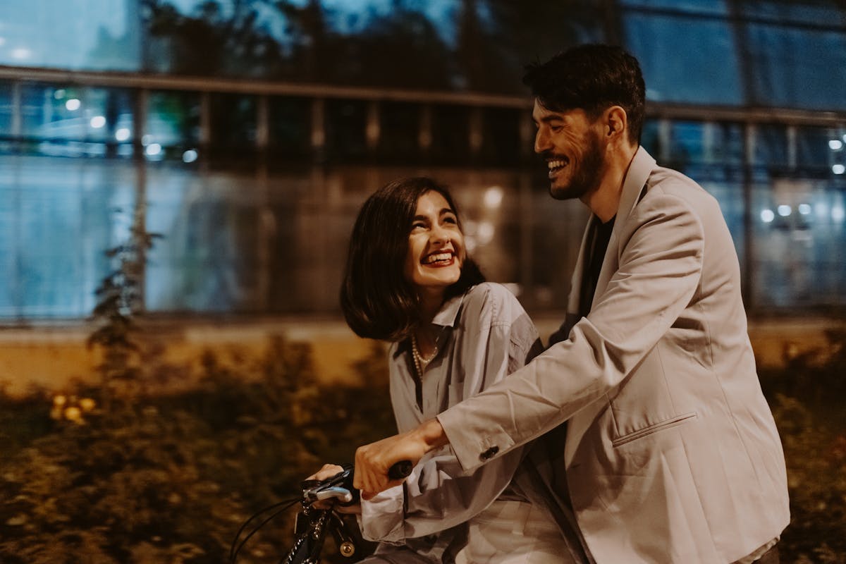 Happy couple riding a bicycle together at night, enjoying a romantic moment.