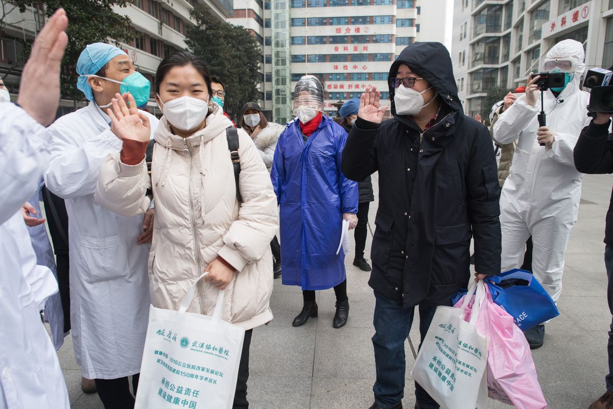 Healthcare workers and people in masks interacting outdoors during COVID-19 pandemic.