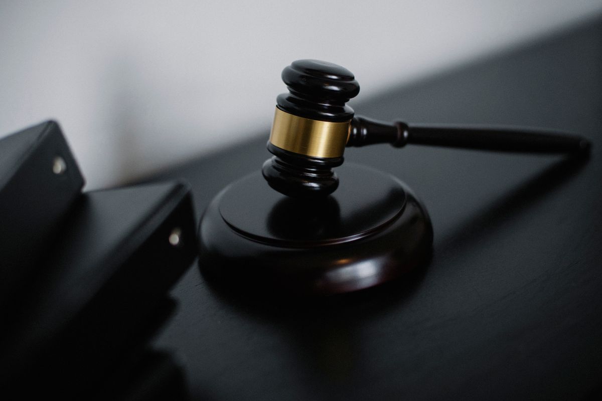 High angle of shiny wooden ceremonial mallet with golden detail placed on judge tale near documents folders