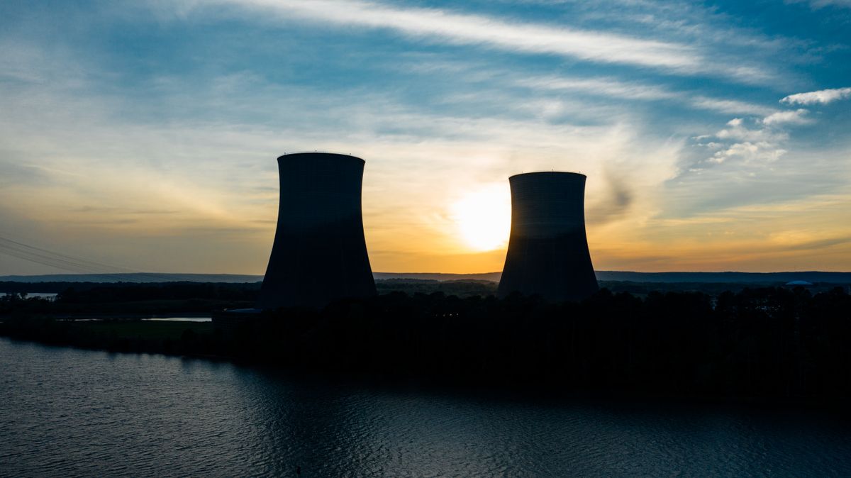 Trump Iran Deal Poll Reveals a Deeper Crisis: Americans Want Peace, Not Confidence 2 Identical cooling tower silhouettes on power plant near rippled river under colorful cloudy sky at sundown