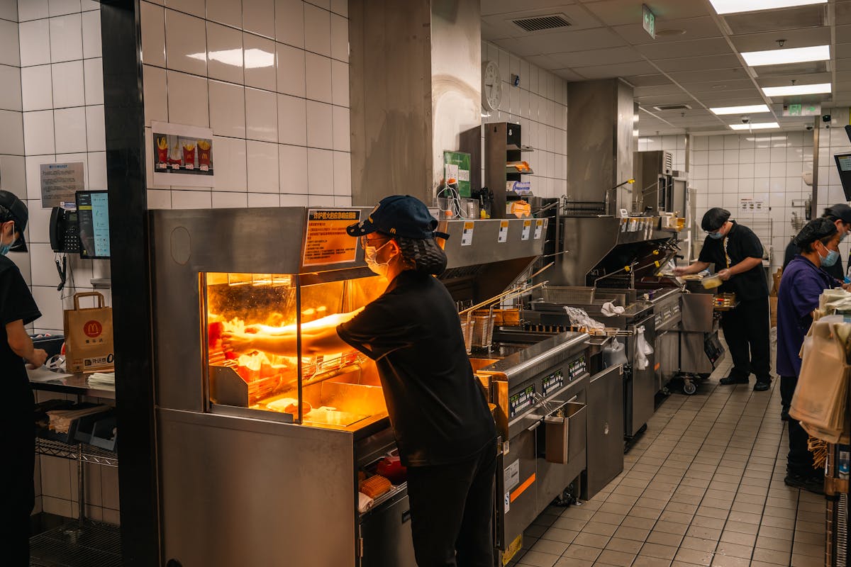 Horror Shift at McDonald’s: Employee Left in ICU After Coworker Throws Scalding Oil 1 Inside view of a bustling fast-food kitchen in Nanjing, China with staff preparing orders.