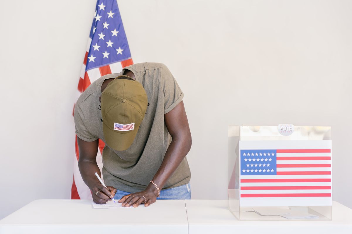 Connecticut Voter Roll Failure Deepens Scrutiny of Richard Blumenthal’s ICE Intervention 1 Man casting vote at polling station with American flag in background.