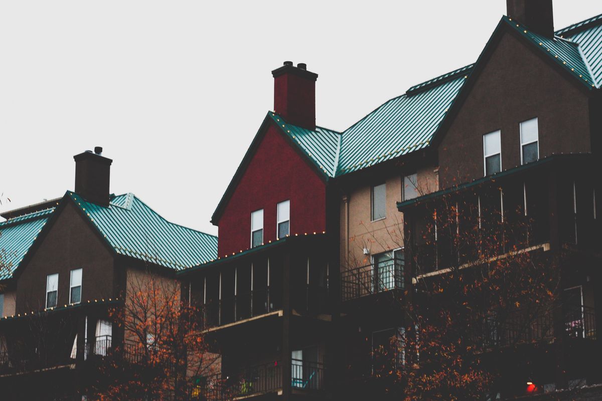 HUD Data Shows Millions of U.S. Households Struggling With Severe Housing Cost Burden 2 Modern urban apartment buildings with distinctive teal metal roofs and balconies.