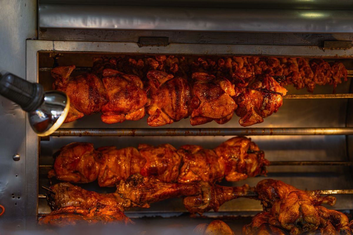 Mouth-watering rotisserie chickens cooking at a street food stall in Ciudad de México, perfect for cuisine lovers.