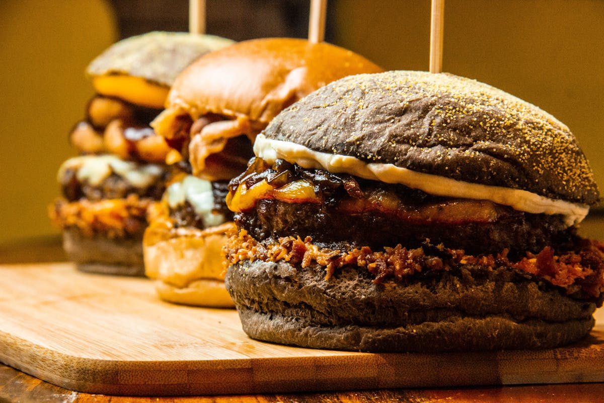 Mouthwatering close-up of gourmet burgers on a wooden board, showcasing delicious textures and toppings.