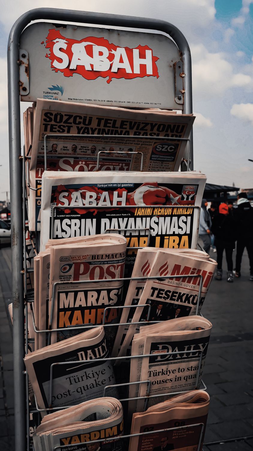 Outdoor display of Turkish newspapers with headlines in focus.