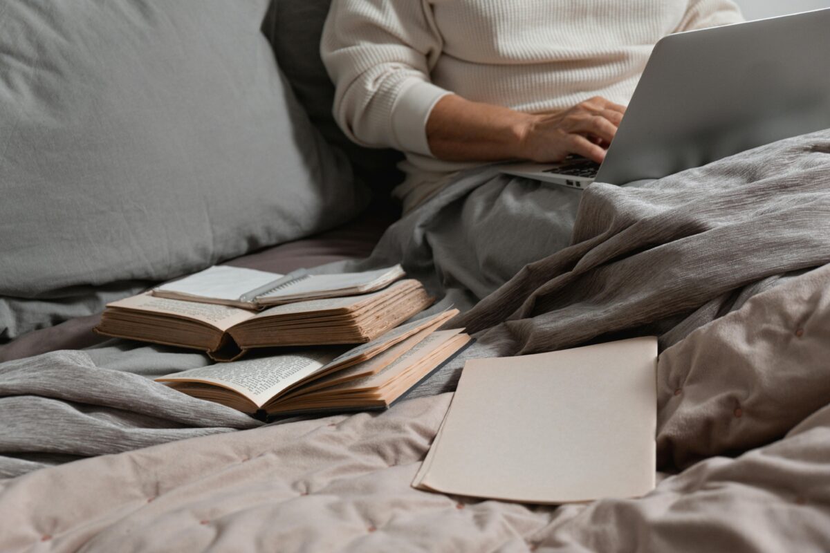 10 Modern Comfort Habits That Reduce Real Productivity 3 a-person-wearing-a-white-sweater-using-a-laptop-near-books