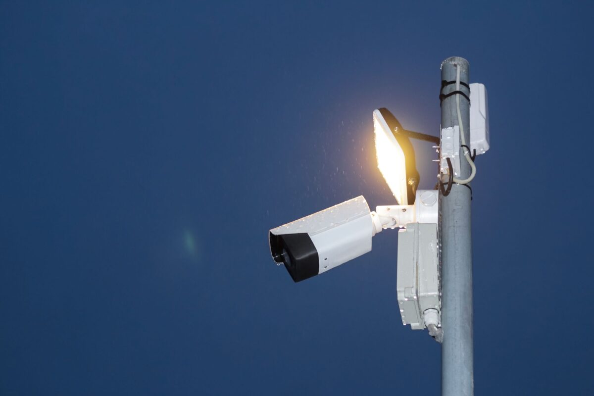 surveillance-camera-and-illuminated-light-under-a-blue-sky