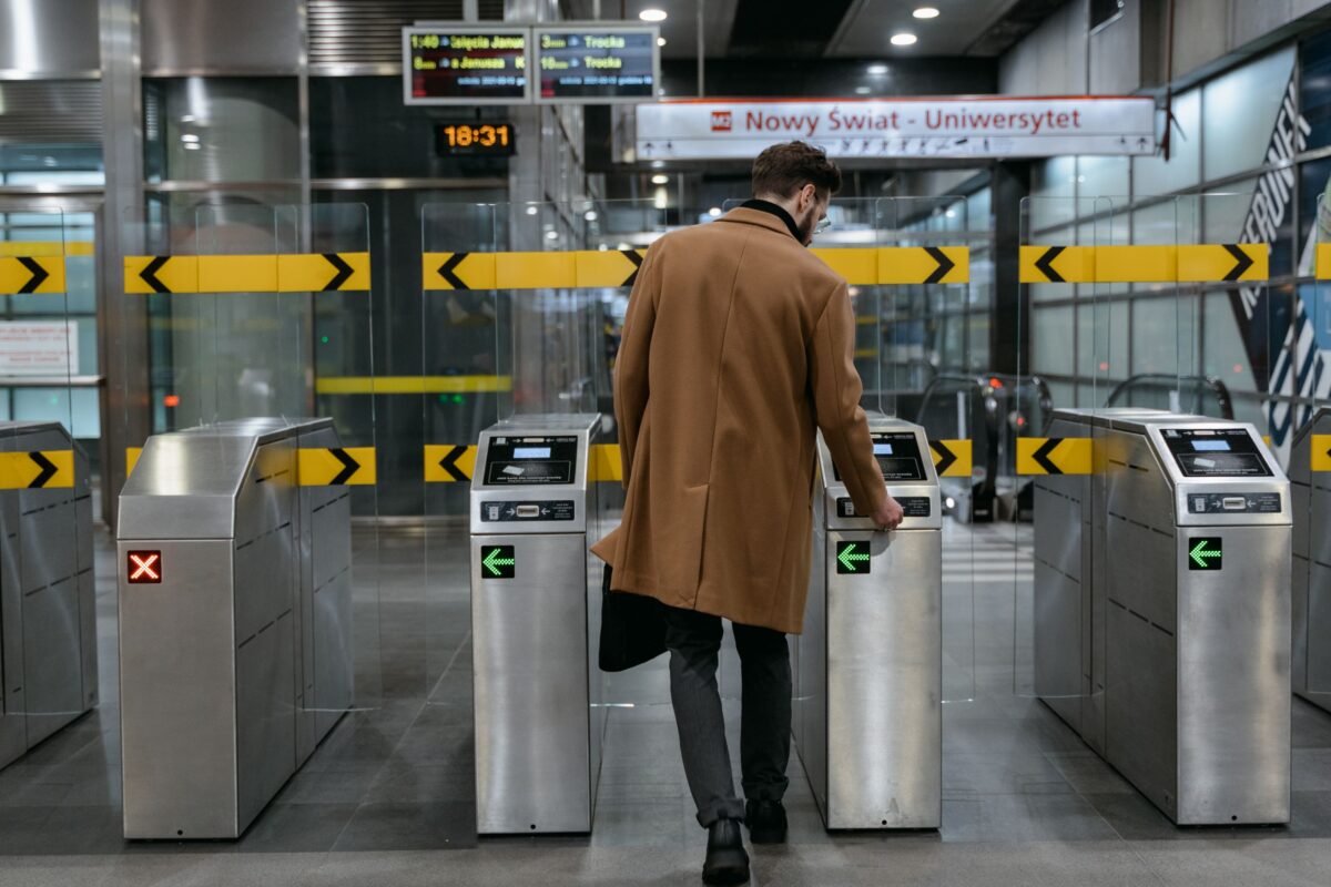 A-man-in-brown-coat-standing-between-ticket-barriers